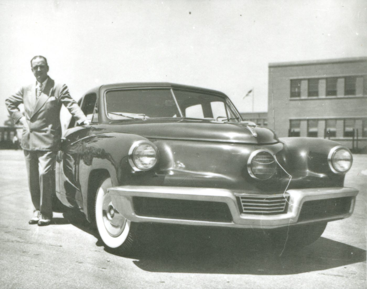 Preston Tucker standing beside a Tucker at the plant